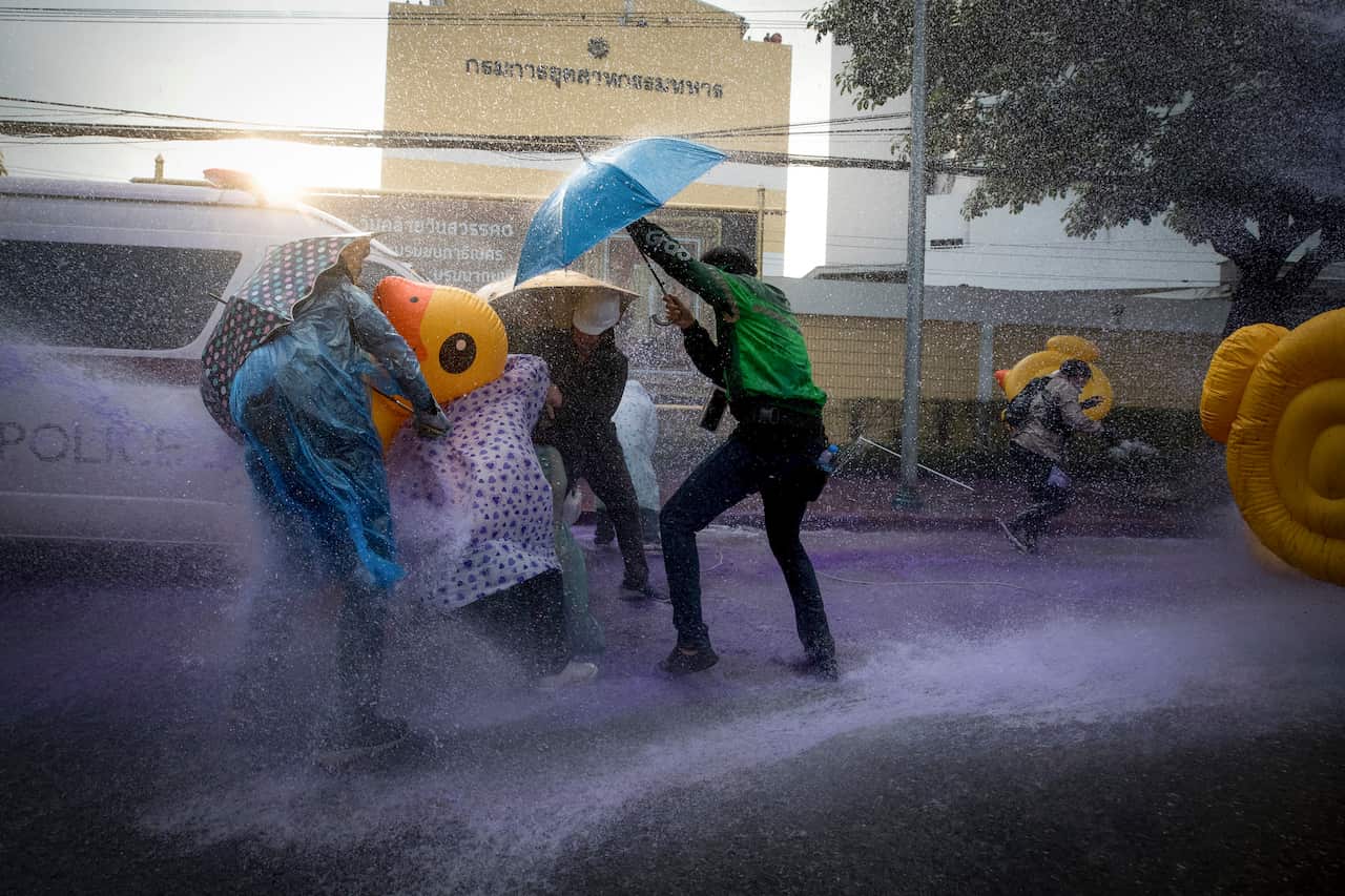 Pro-democracy protesters take cover with inflatable ducks and umbrellas as police fire water cannon