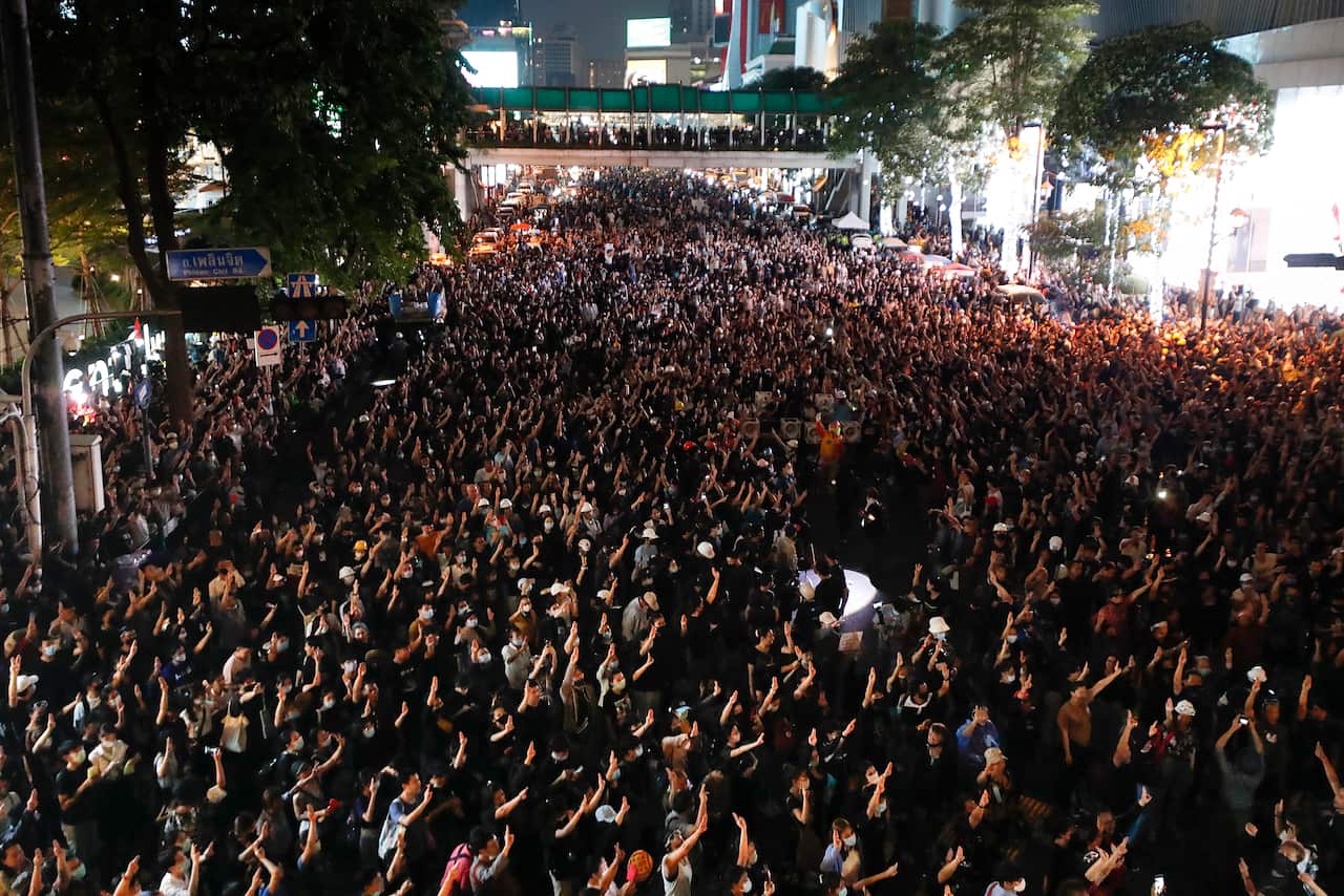 Pro-democracy protesters flash the three-finger protest salute during an anti-government rally at a major intersection in Bangkok, Thailand. 