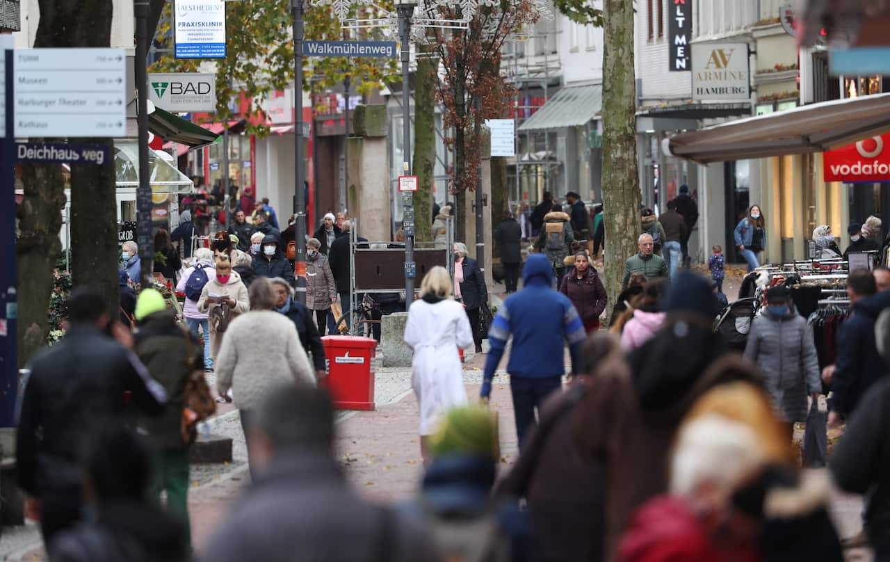 Shoppers with and without face masks walk at the pedestrian zone in Hamburg-Harburg, northern Germany. 
