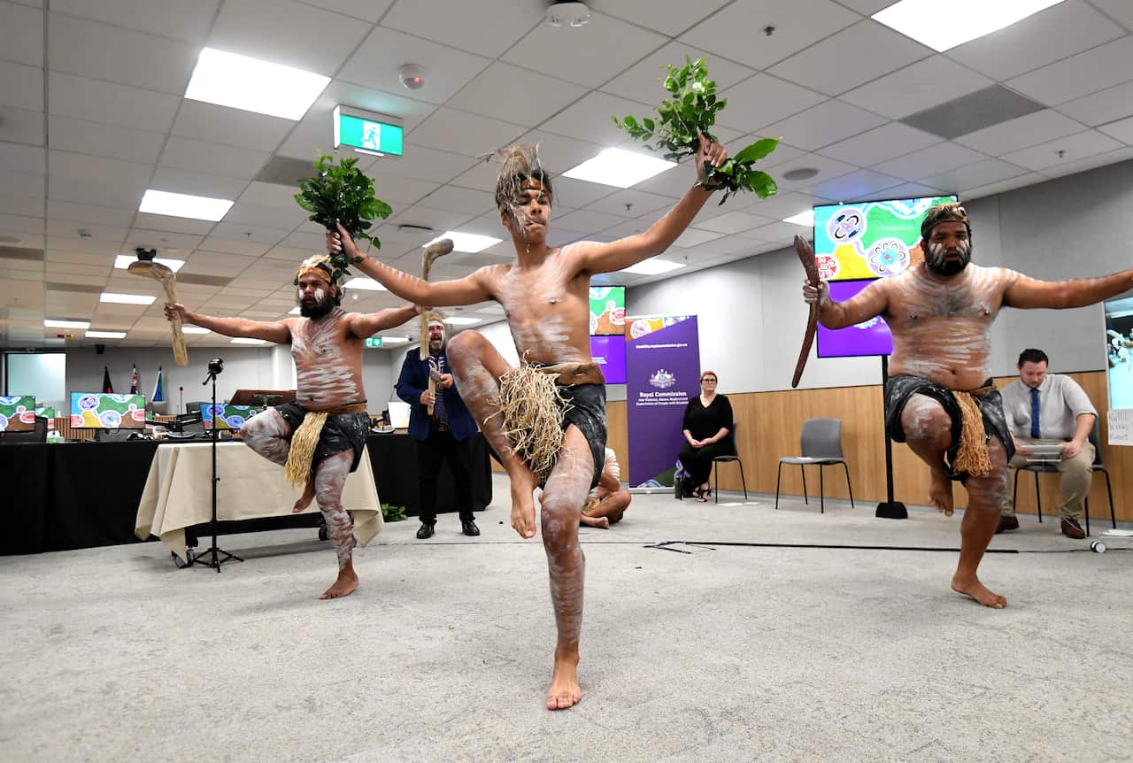 An Aboriginal dance group performs a cleansing ceremony at the Brisbane headquarters of the disability royal commission. 