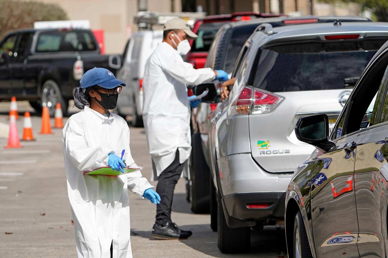 Healthcare workers process people waiting in line at a United Memorial Medical Center COVID-19 testing site in Houston.