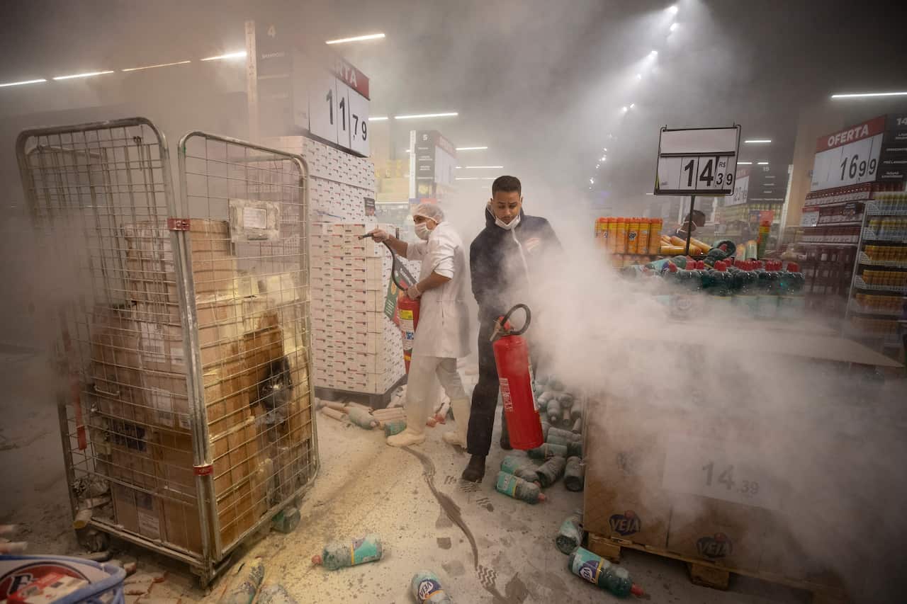 Employees try to douse fires inside a Carrefour supermarket during a protest against the murder of  Joao Alberto Silveira Freitas.