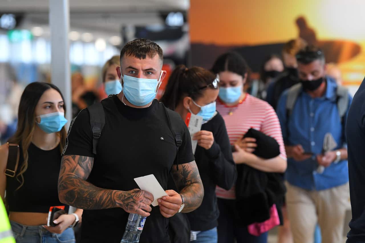 People wearing face masks are seen waiting to board a flight to Sydney at Melbourne.
