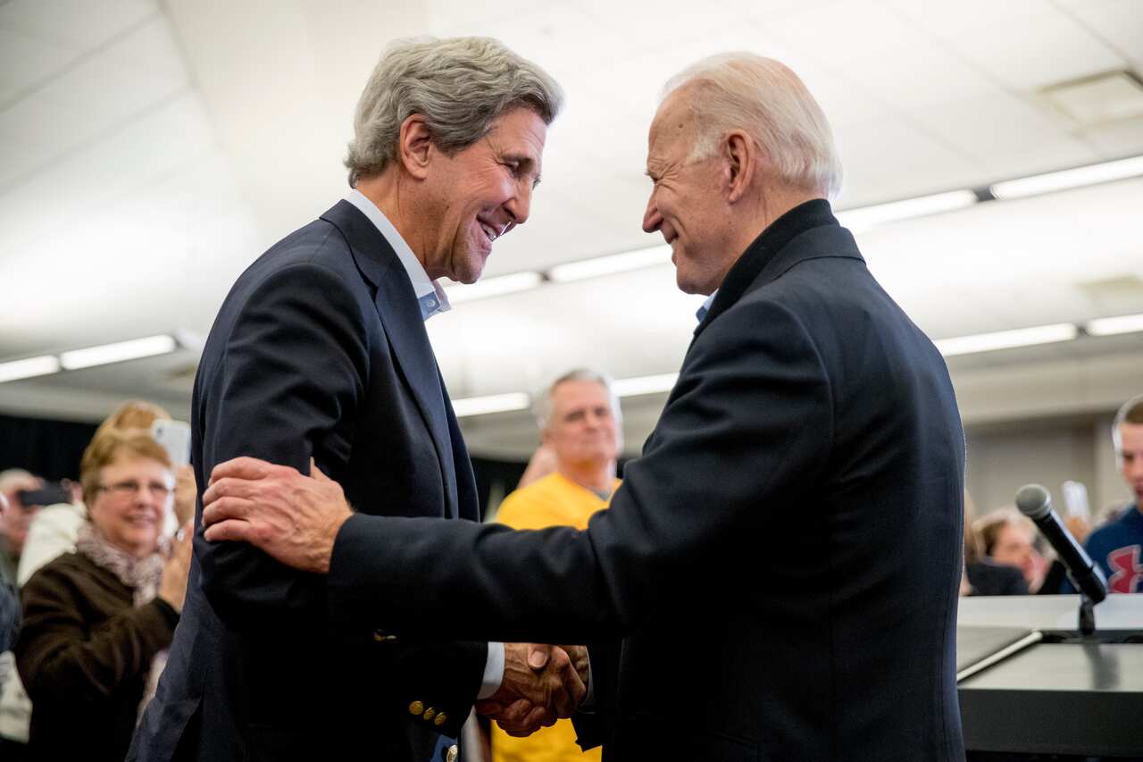 Joe Biden smiles as former Secretary of State John Kerry, left, speak at a campaign stop in North Liberty, Iowa in February, 2020. 
