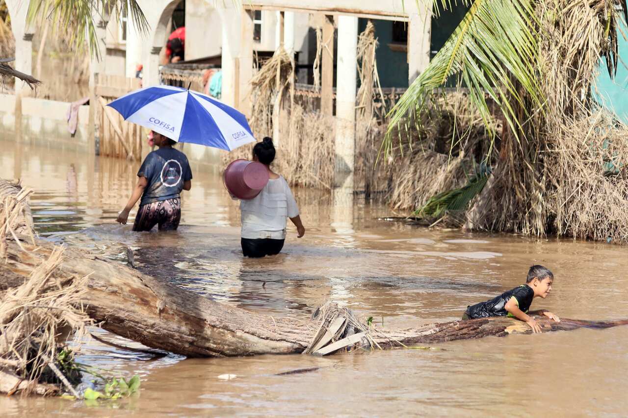 People affected by storms Eta and Iota navigate a flooded street in La Guadalupe, Honduras, on 30 November.