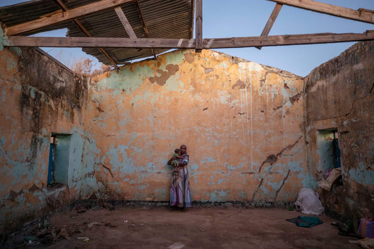 A woman who fled the conflict in Ethiopia's Tigray region holds her child inside a temporary shelter at Umm Rakouba refugee camp in Qadarif, Sudan.