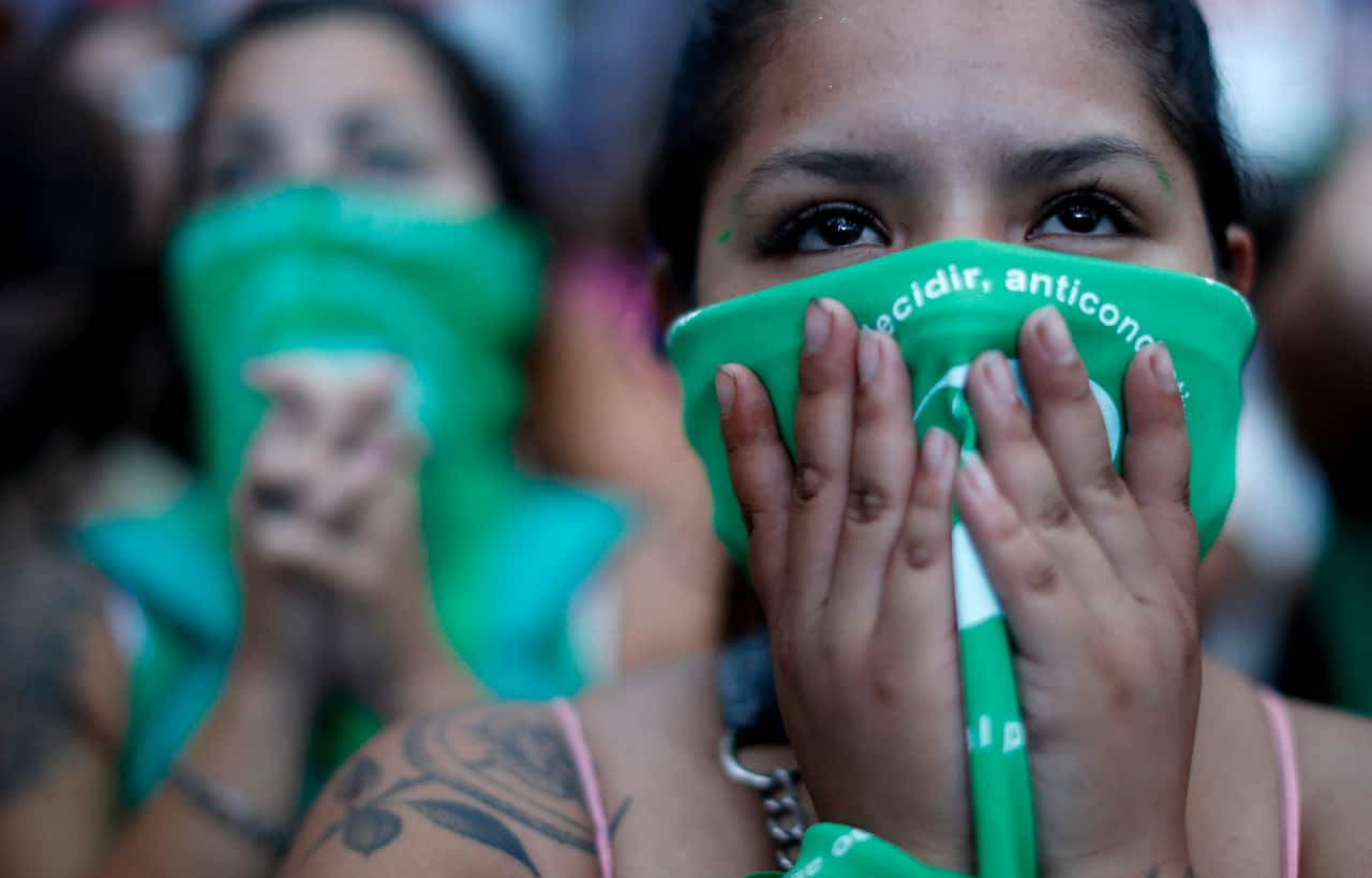 Abortion-rights activists watch politicians debate the bill on a big screen outside Congress in Buenos Aires