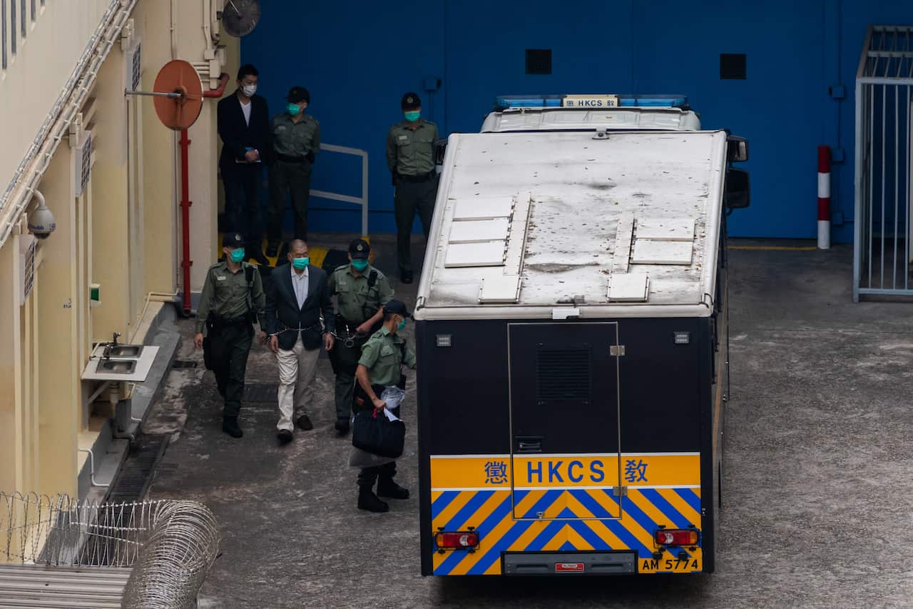 Jimmy Lai, handcuffed, is escorted by prison guards to board a Correctional Services Department vehicle to the West Kowloon Magistrates' Courts on 12 December. 