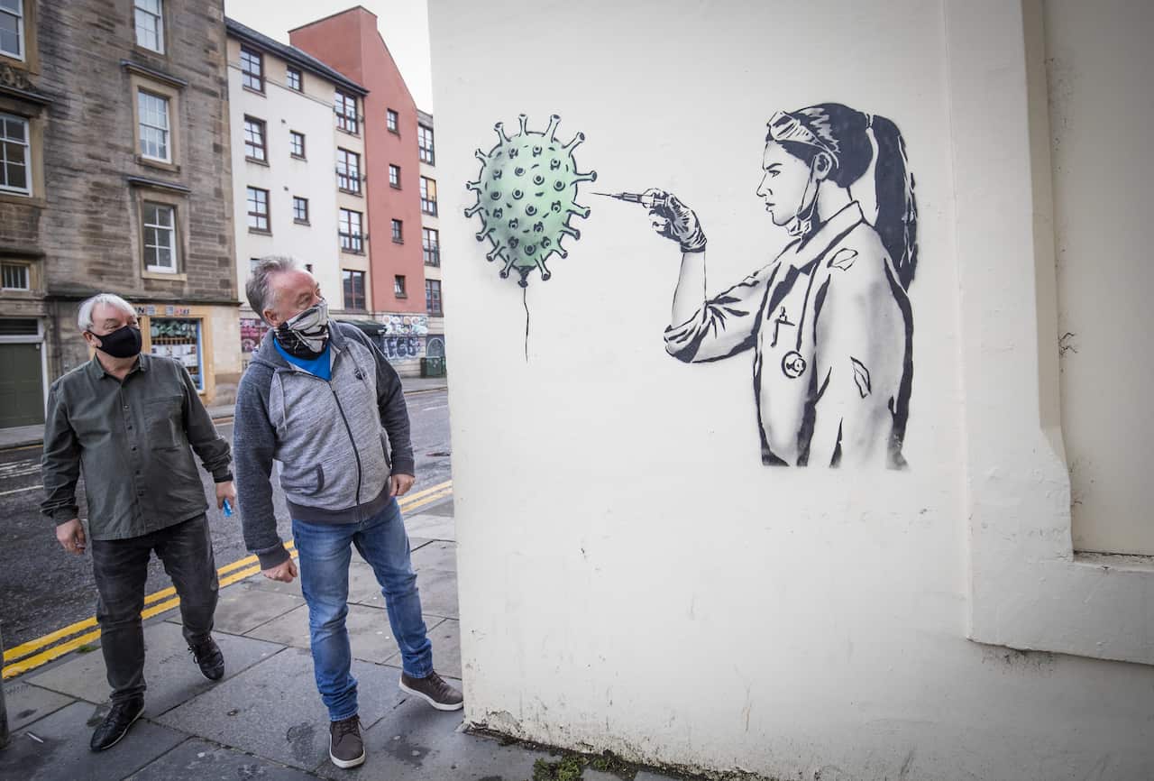 Members of the public take a closer look at new artwork created by street artist The Rebel Bear in Edinburgh city centre.