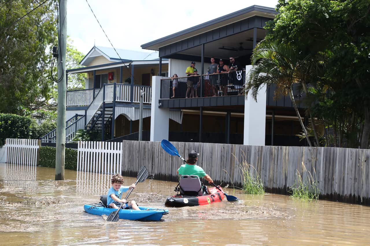 Residents of Tumbulgum paddle their kayaks down a street in northern NSW last week. 