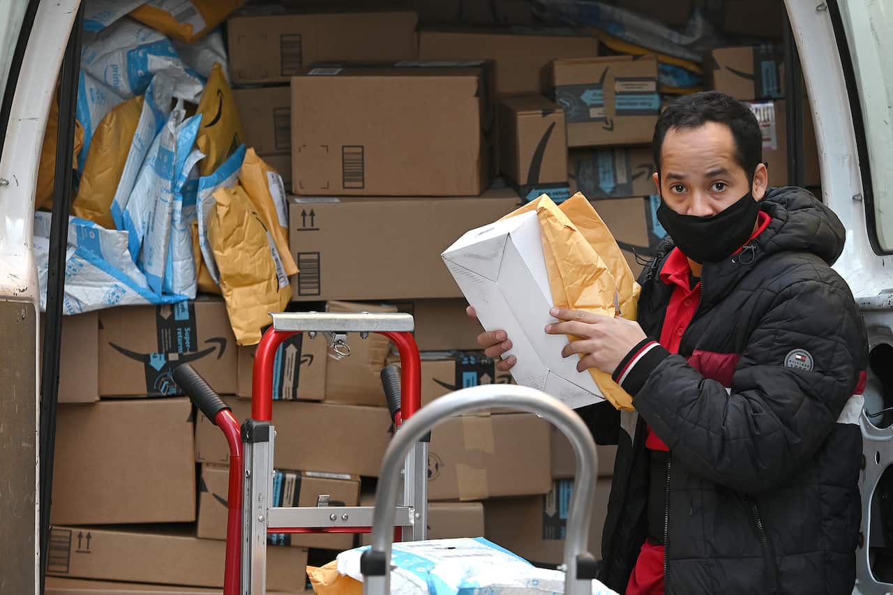 A man stands at the back of his van filled with packages waiting to be delivered in New York.