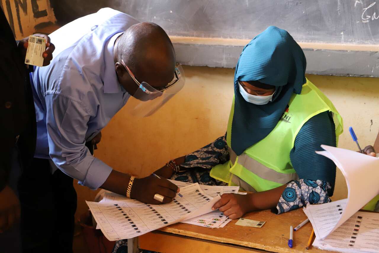 An electoral official checks the voter registration of a man at a polling station in Niamey.