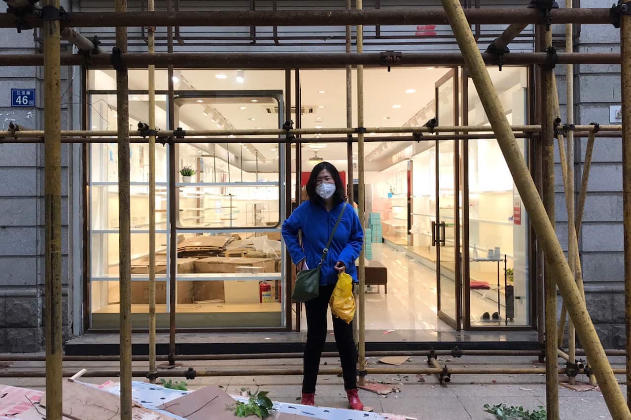 Zhang Zhan stands near scaffolding outside a shop during a visit to Wuhan.