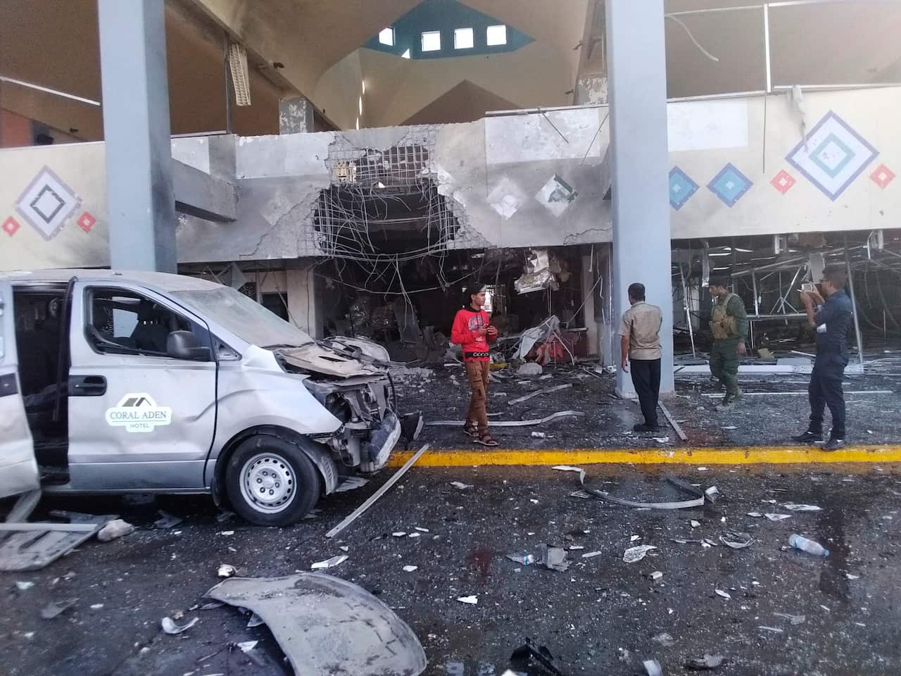 Bystanders and a soldier stand near a damaged portion of the airport of Aden.