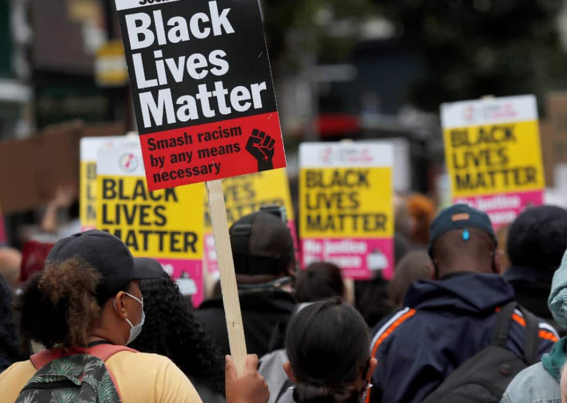 Black Lives Matter protesters hold posters as they march in London on Sunday, August 30, 2020,