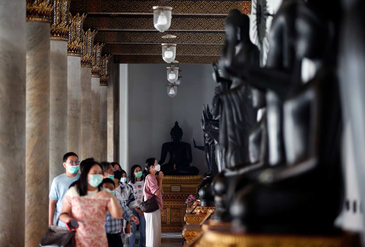 Devotees wearing face masks pray to ancient Buddha statues to mark the start of the new year at the Marble Temple, in Bangkok on 1 January.