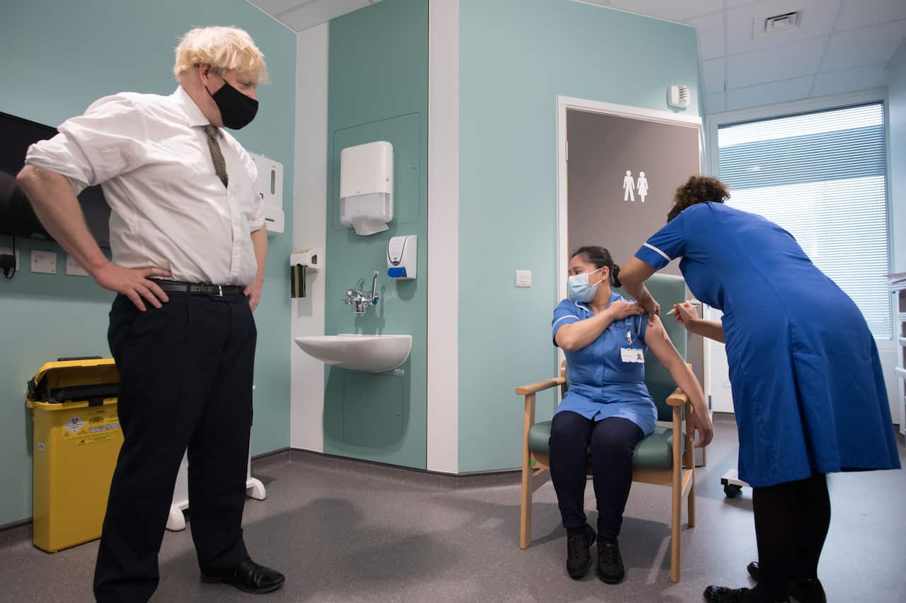 Prime Minister Boris Johnson watches as Jennifer Dumasi receives the Oxford/AstraZeneca COVID-19 vaccine at Chase Farm Hospital in north London on 4 January.
