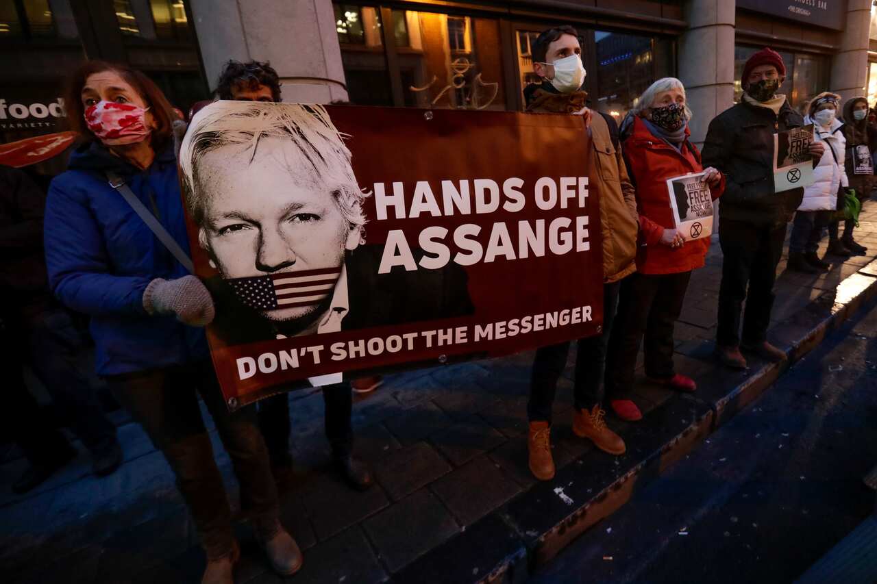 Demonstrators hold a placard with Julian Assange's photo in front of the British Embassy