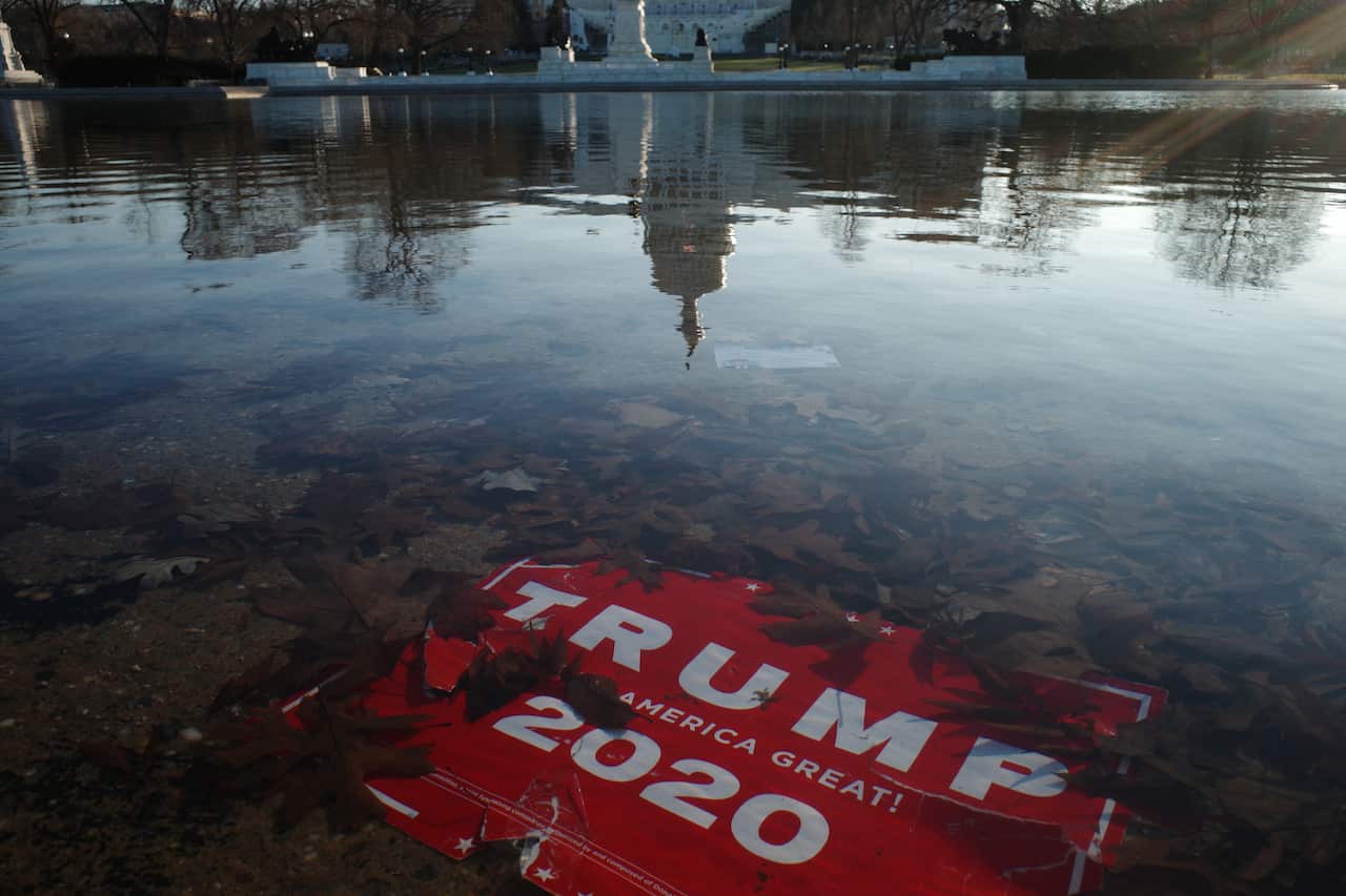 A 'Trump 2020' placard is submerged as the US Capitol Dome reflection is seen on the water of the US Capitol reflecting pool