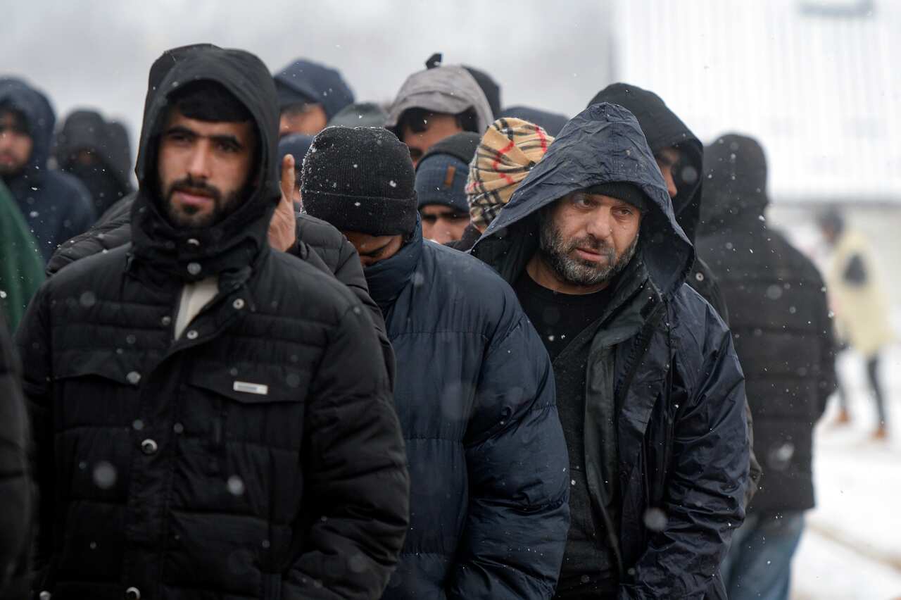 Migrants wait in lines for food handouts during a snowfall at the Lipa camp, outside Bihac, Bosnia.