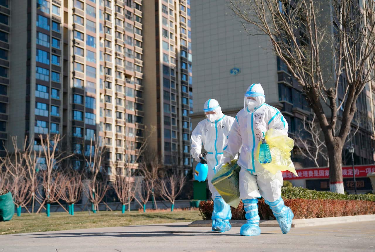 In this photo released by China's Xinhua News Agency, workers carry a container of coronavirus test samples outside a neighbourhood in Shijiazhuang on Friday.