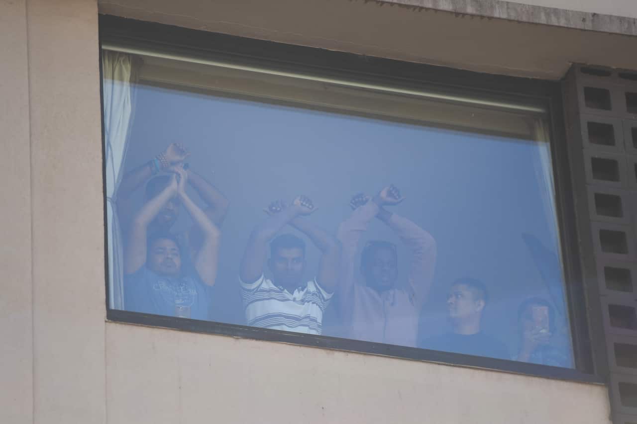 Refugees gesture towards protesters at the Park Hotel in Melbourne, Saturday, January 09, 2021. (AAP Image/Erik Anderson) NO ARCHIVING