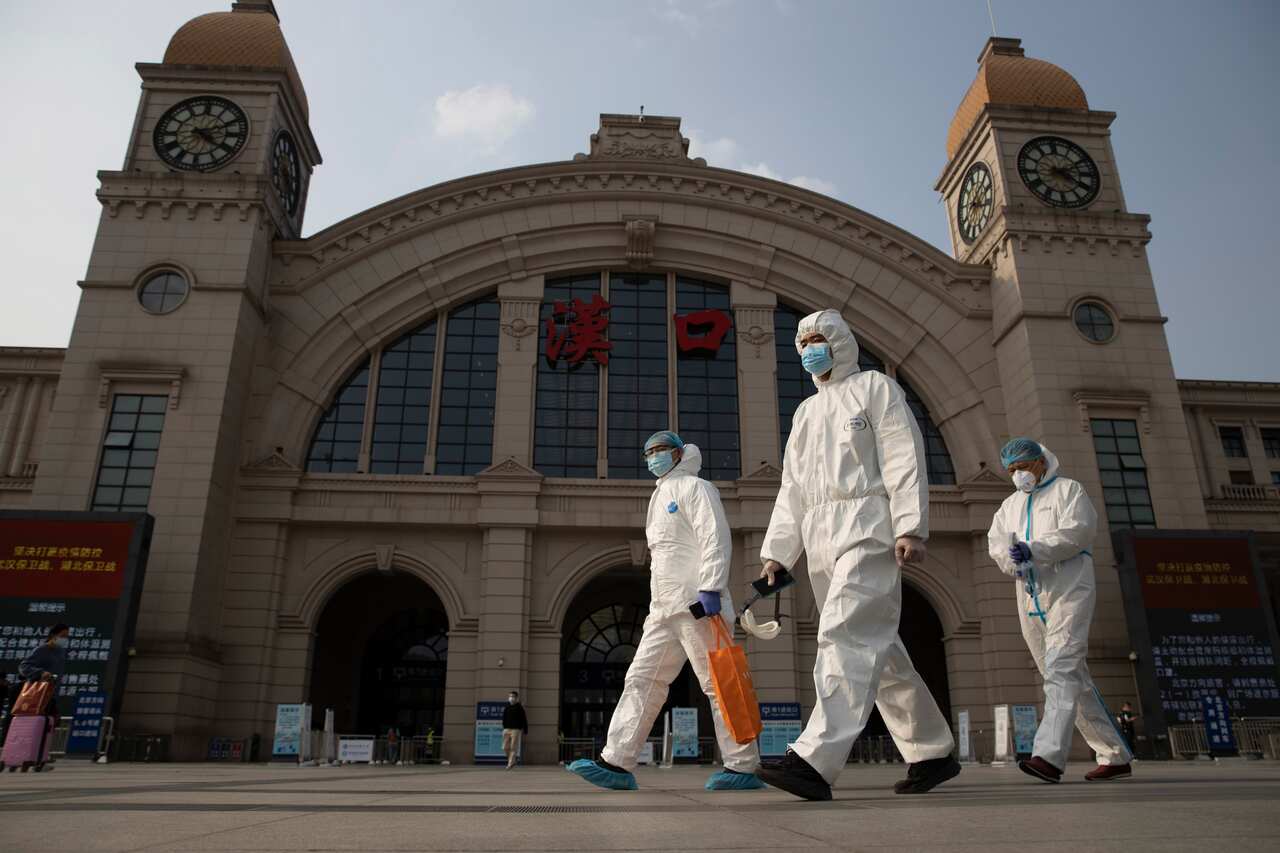 Workers in protective suits walk past the Hankou railway station in Wuhan in April, last year.