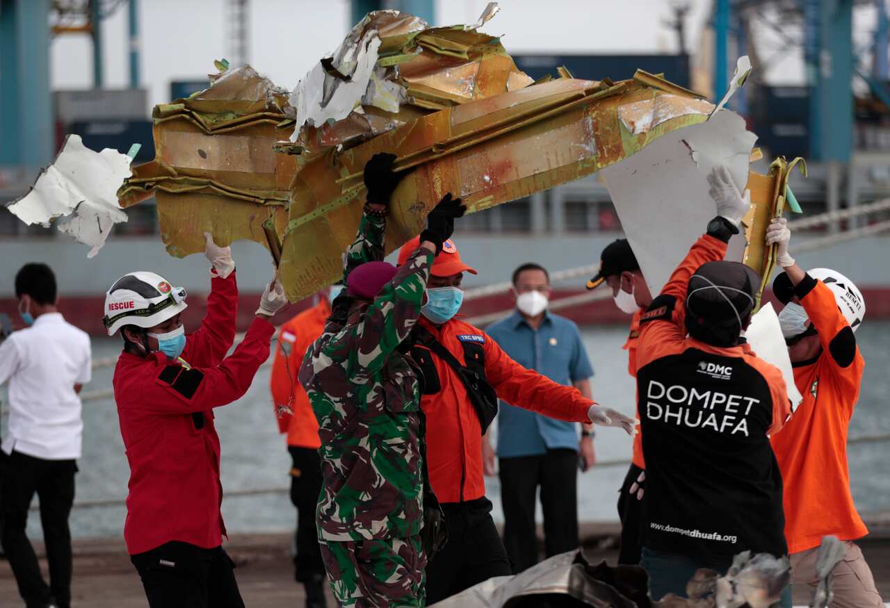 Rescuers carry a part of the aircraft recovered from the Java Sea.