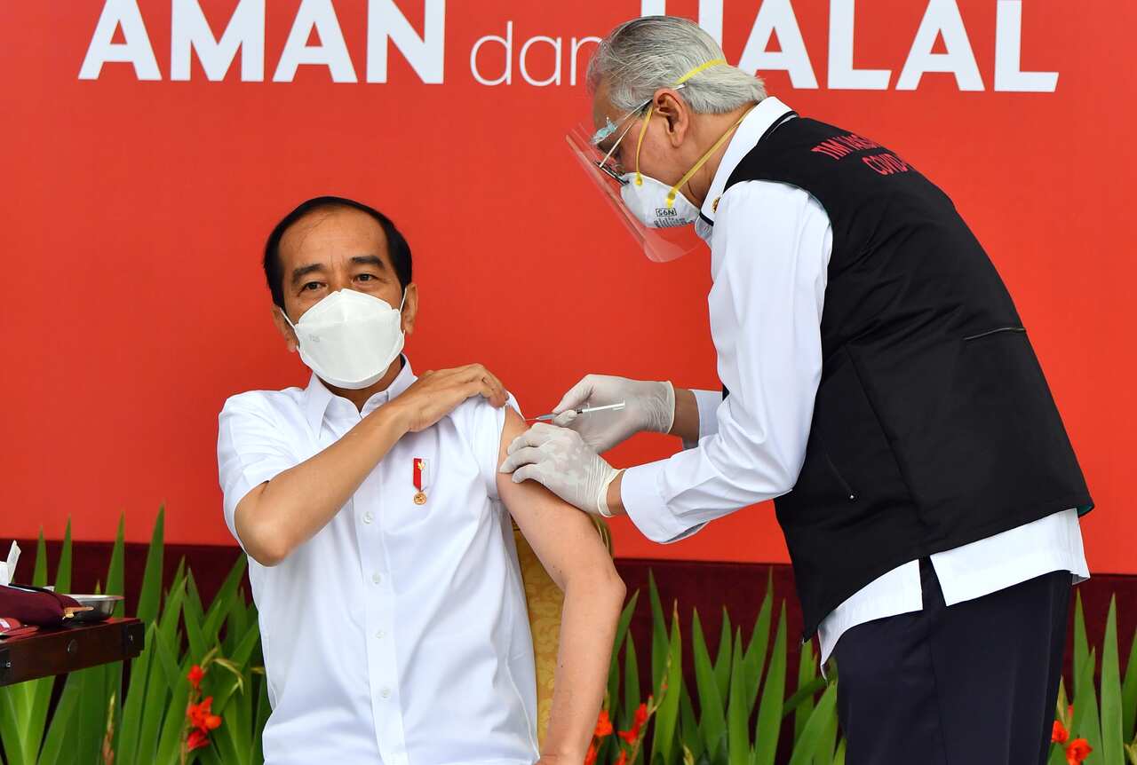 A handout photo made available by the Presidential Palace Indonesia shows Indonesian President Joko Widodo (L) injected with a COVID 19 vaccine. 