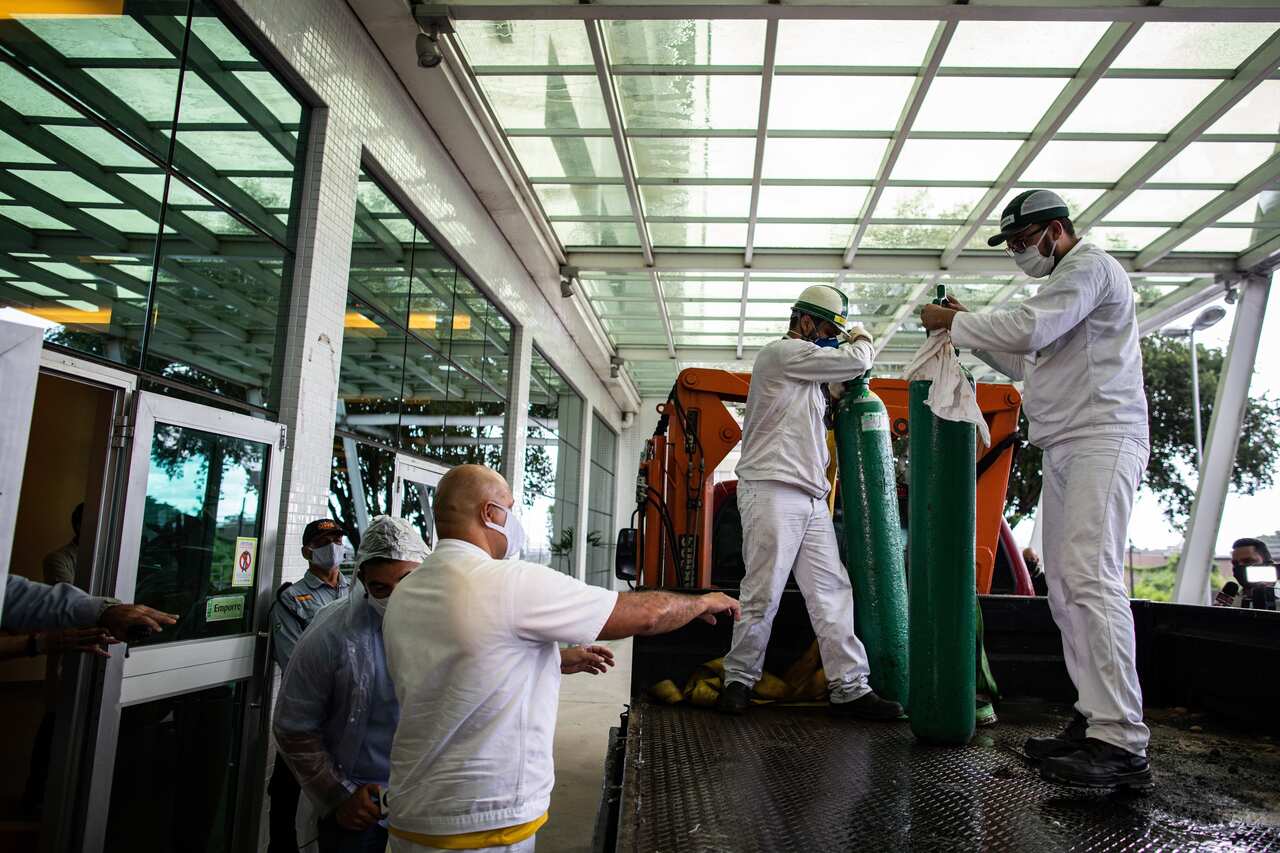 Workers carry oxygen cylinders at the Getulio Vargas University Hospital, in Manaus, Brazil, 14 January 2021.