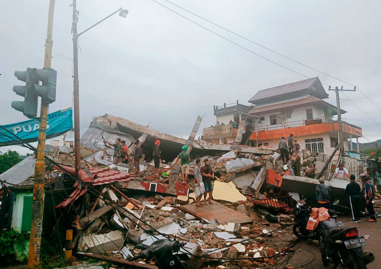 Residents inspect an earthquake-damaged buildings in Mamuju, West Sulawesi following the earthquake on 15 January, 2021. 