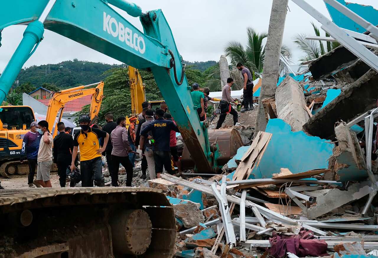 Residents inspect an earthquake-damaged buildings in Mamuju, West Sulawesi, Indonesia, Friday, Jan. 15, 2021. 
