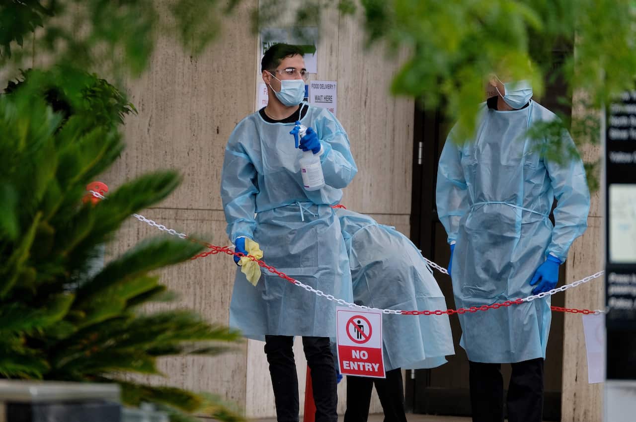 Cleaning staff wearing full PPE gear are seen cleaning outside the View Hotel in Melbourne, 18 January 2021.