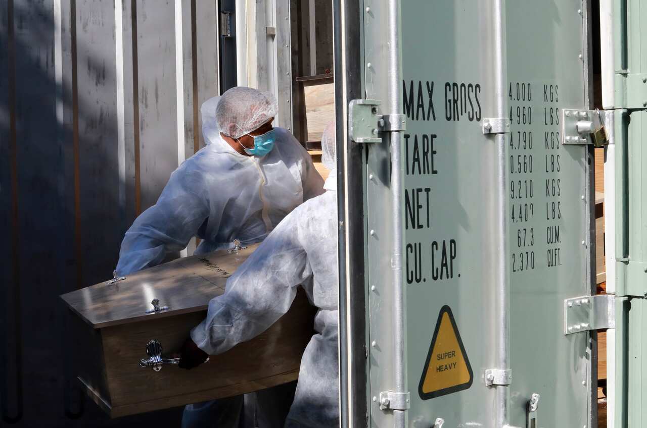 Funeral workers place a coffin inside a refrigerated container at AVBOB's funeral parlour in Bellville, Cape Town, South Africa.
