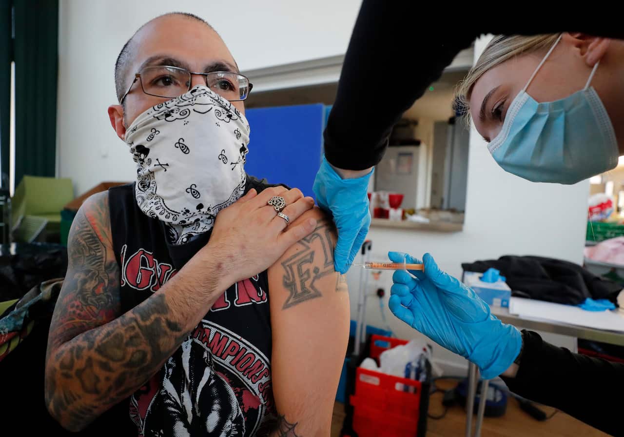 Apprentice Nursing Associate Ellie Bull administers a dose of the AstraZeneca vaccine to a homeless person at east London, Friday, Feb. 5, 2021. 