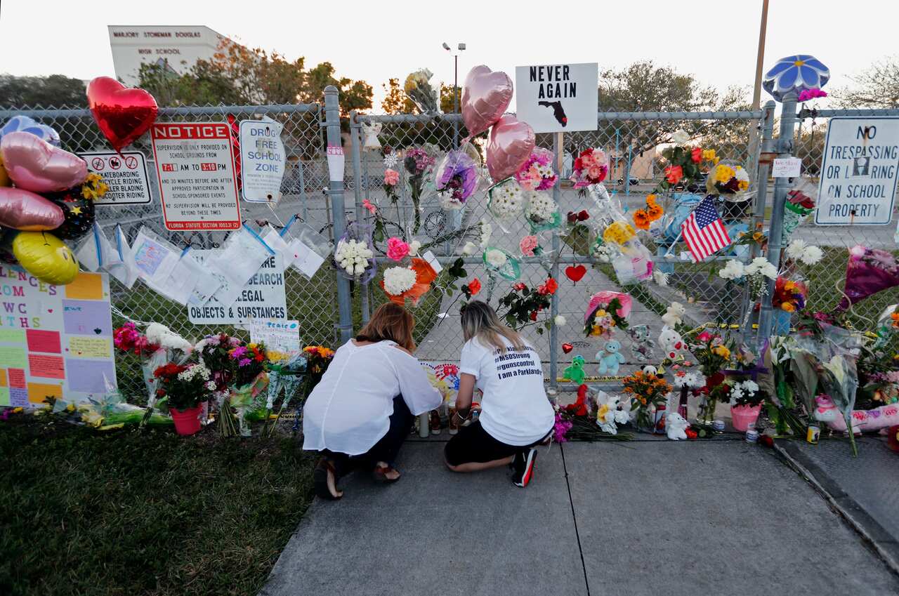 People light candles at a makeshift memorial outside Marjory Stoneman Douglas High School, where 17 people were killed in a mass shooting in 2018.
