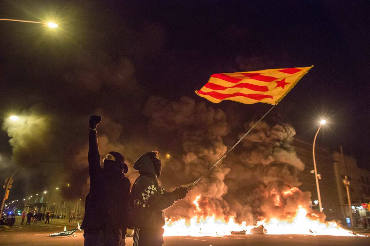 A demonstrator waves an independent flag in front of burning containers during demonstrations on Friday.