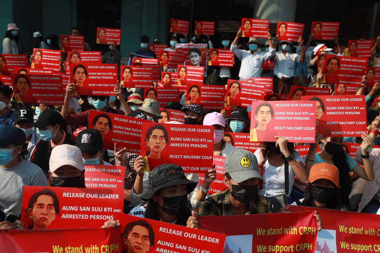 Anti-coup protesters hold posters with images of deposed Myanmar leader Aung San Suu Kyi as they gather outside the Hledan Centre in Yangon