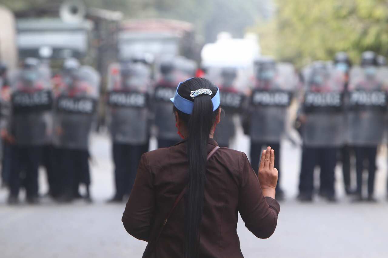 A female protester flashes a three-fingered salute in front of police in Mandalay, Myanmar, Saturday, February 20, 2021