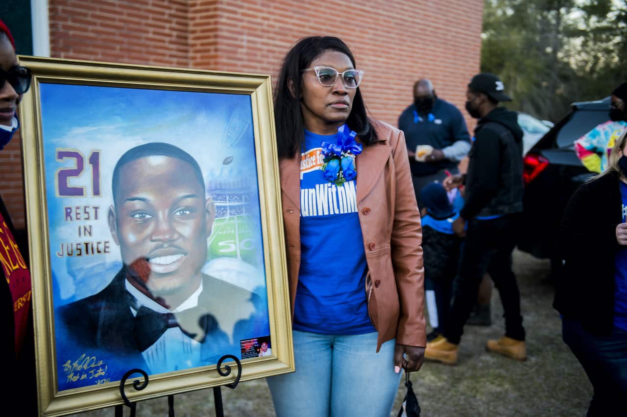 Wanda Cooper-Jones, mother of Ahmaud Arbery, stands with a painting of her son at a candelight vigil in his honour on 23 February, 2021.