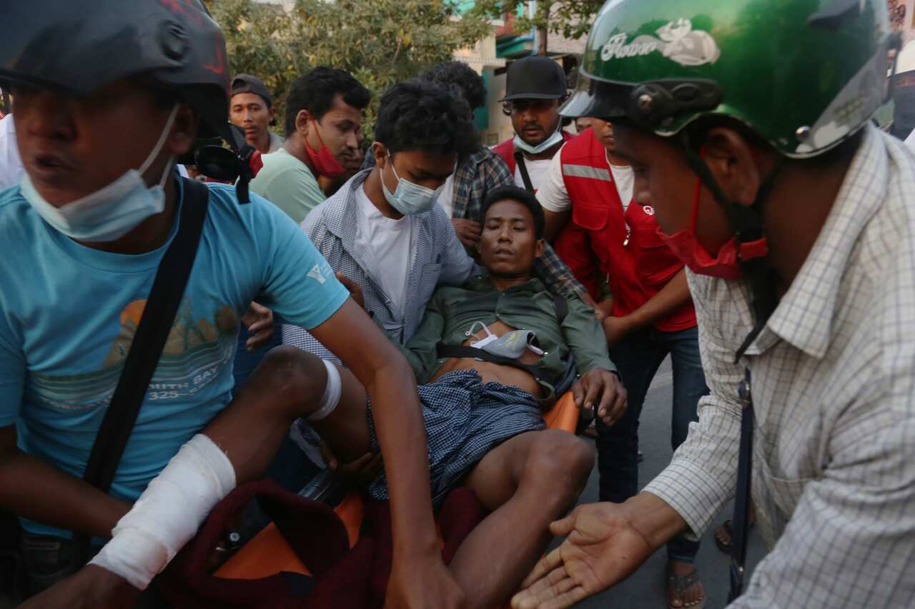 People carry an injured man after police cracked down on demonstrators during a protest against the military coup in Mandalay, Myanmar, 28 February 2021.