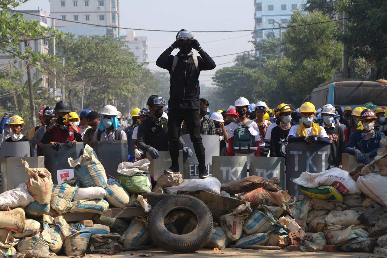 Protesters take positions behind a makeshift barricade in Yangon, Myanmar, Sunday, March 7