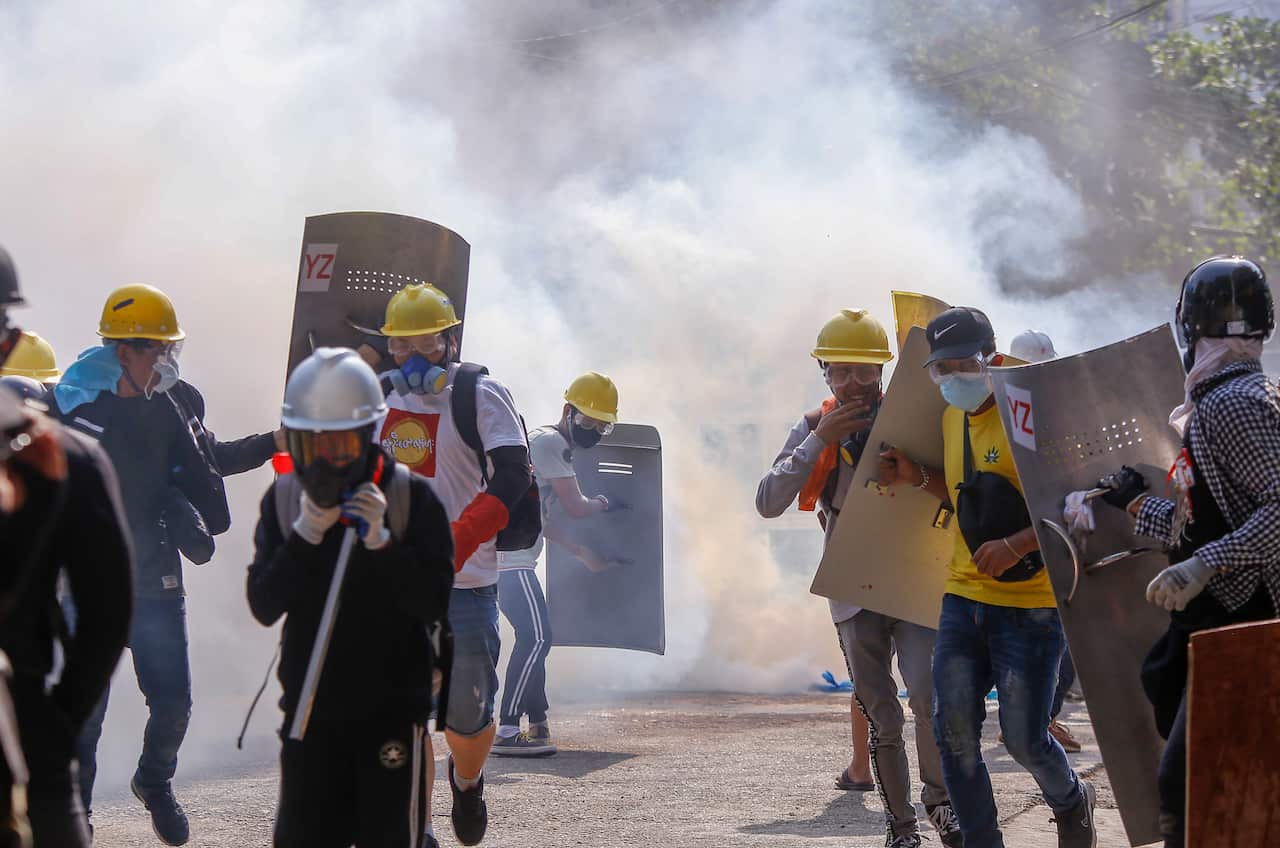 Anti-coup protesters retreat after riot policemen fire teargas in Yangon, Myanmar, March 9, 2021.