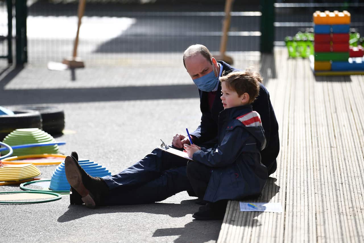 Britain's Prince William talks with a child in the playground during a visit with Kate, Duchess of Cambridge to School21.