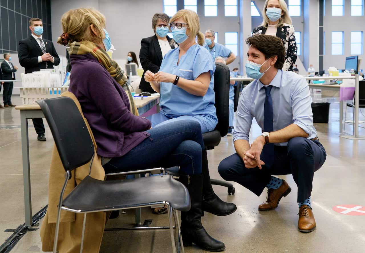 Canada's Prime Minister Justin Trudeau chats with a woman about to receive a COVID-19 vaccine while touring a vaccination clinic in Montreal.