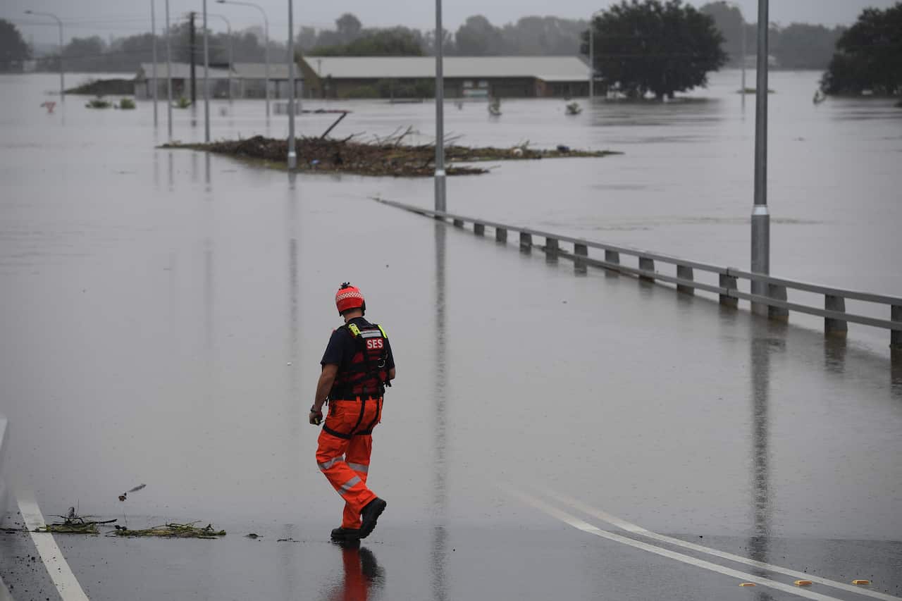 SES flood rescue team members inspect floodwaters flowing over the New Windsor Bridge at Windsor in north western Sydney on 23 March, 2021. 