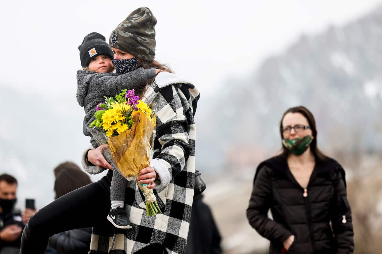A woman and her child bring flowers to a memorial outside a Boulder grocery store where multiple people, including a police officer, were killed in a shooting.