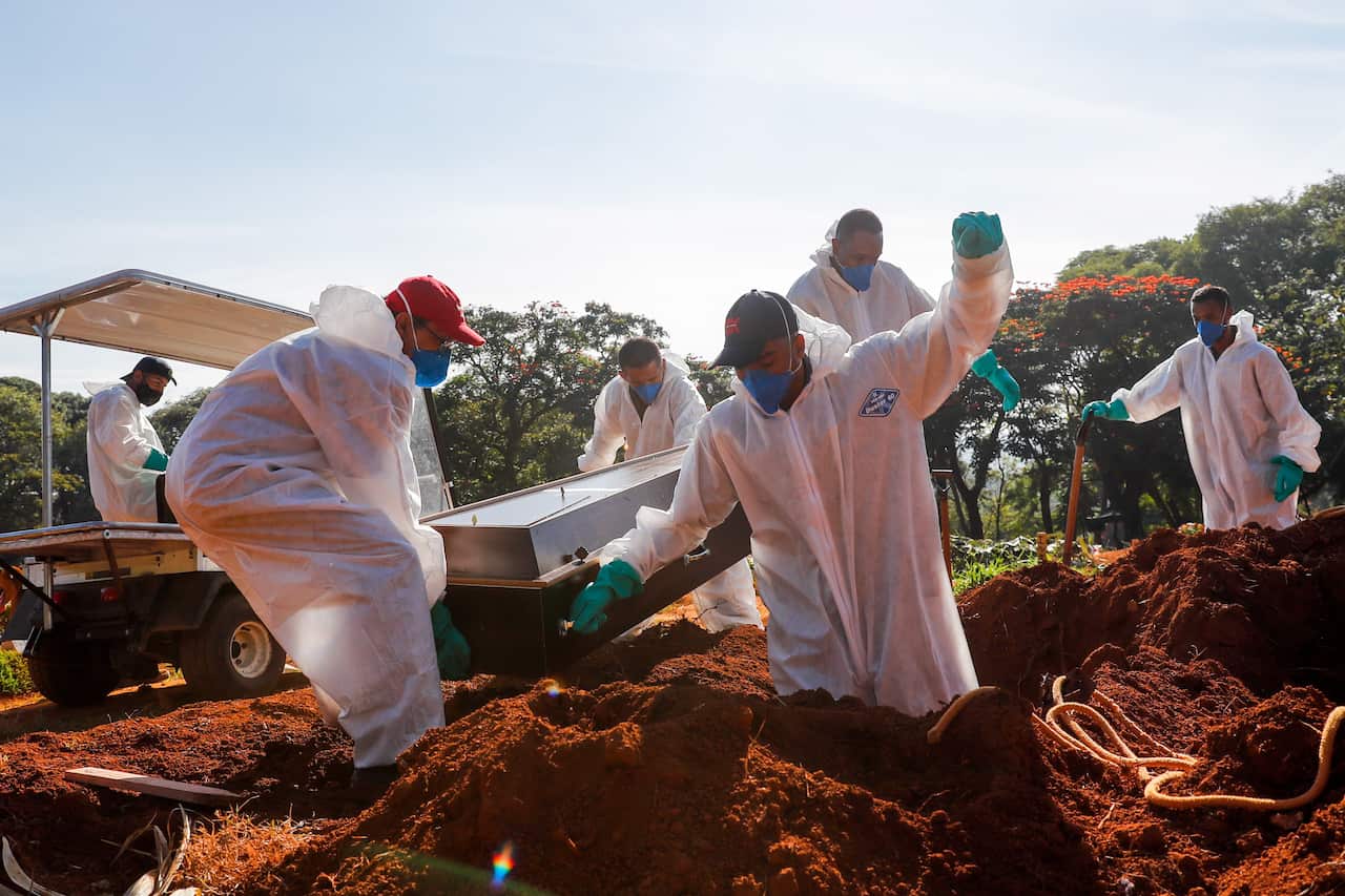 Workers place a coffin inside a grave in the Vila Formosa cemetery in Sao Paulo, Brazil