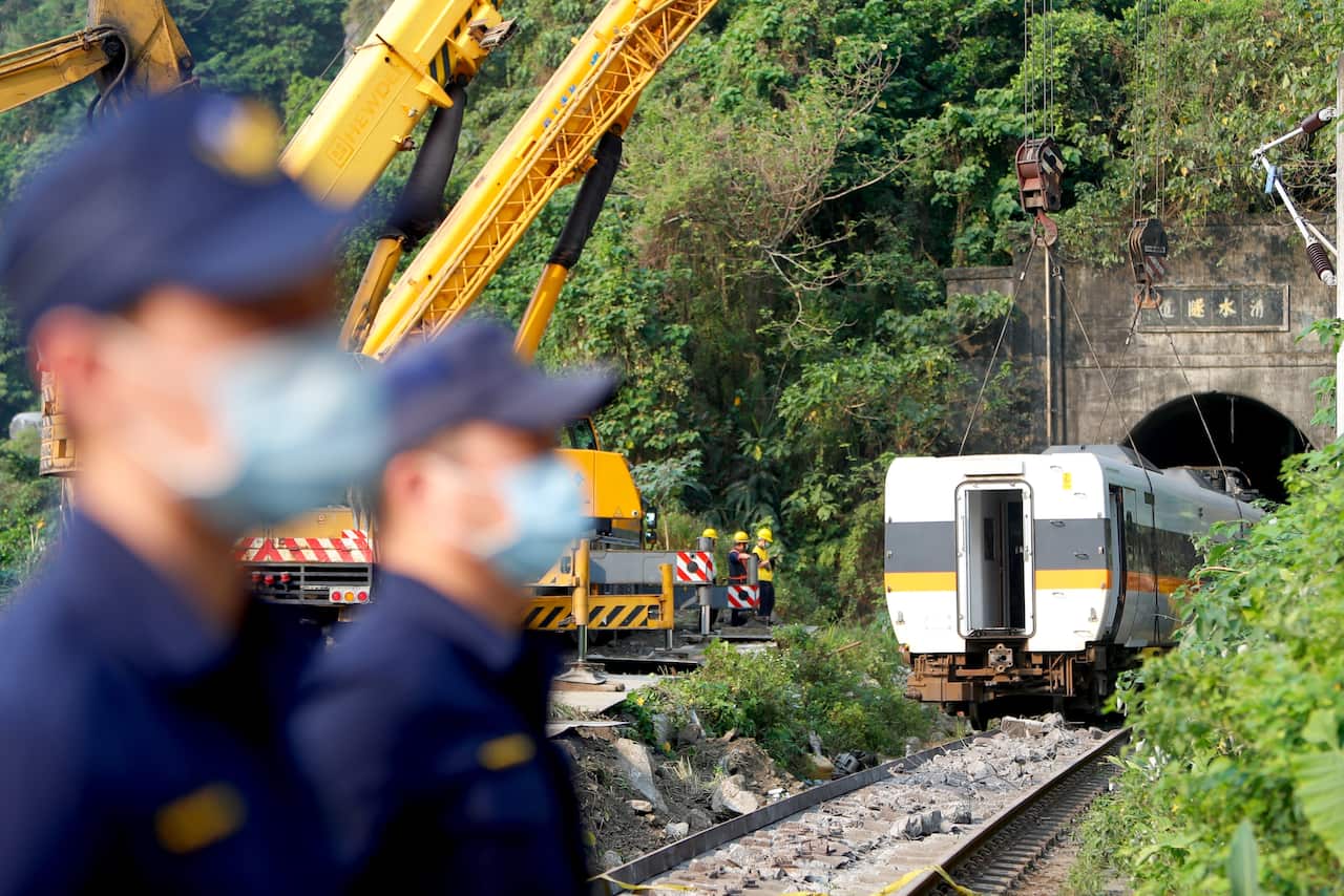 A damaged train carriage is lifted and removed from the track