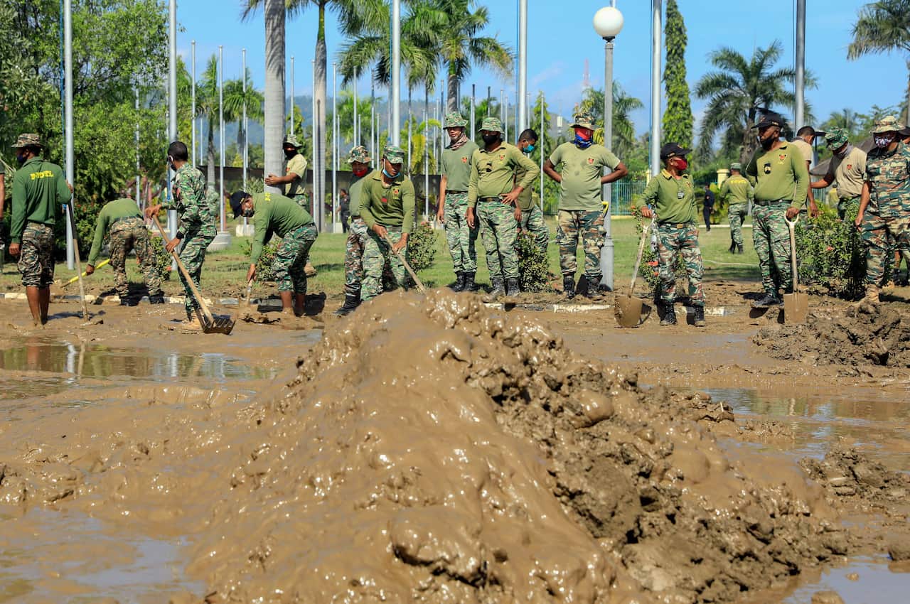 East Timorese military personnel clean up the mud outside the presidential office in the aftermath of floods in Dili, East Timor, also known as Timor Leste.